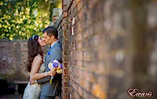 Bride and groom kiss against a brick wall.