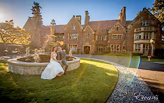 Bride and groom have a seat by the fountain as they pose for wedding portraits.