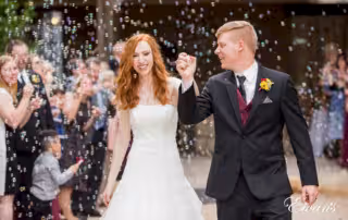 Smiling while exiting their ceremony the couple feels immense amounts of joy and pure happiness. Their friends and family blow bubbles while this moment is shared with all of them.