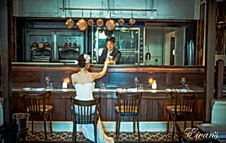 The groom serves a drink to the love of his life at a modern bar with a classic yet elegant twist.