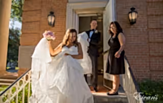 The groom helps carry his bride's gown down the steps as they exit the chapel.