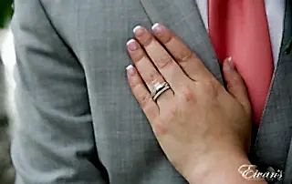 The bride places her hand onto the chest of her groom showing off her new wedding ring.