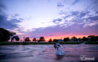 The bride and groom dance together in a beautiful environment under a tremendous sunset.