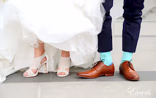 The bride and groom show off their shoes within their perfect wedding day look.