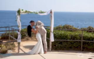The bride and groom kiss under a stunning archway together kissing and celebrating their love.