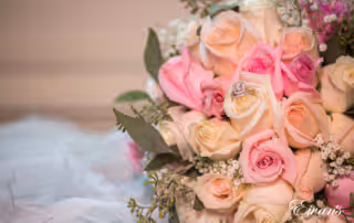 The brides bouquet of white and pink roses is also holding the ring that will soon be placed onto her finger.