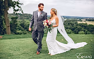 man in black suit and woman in white wedding dress holding bouquet of flowers